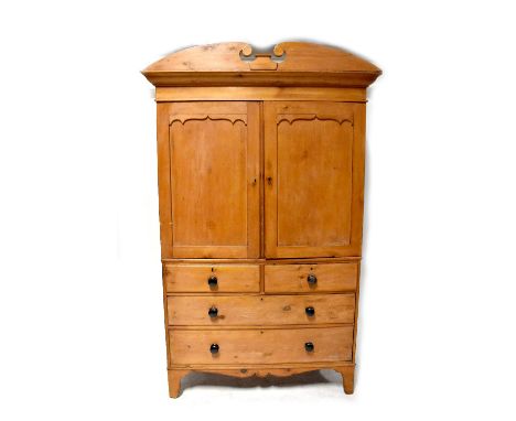 A Victorian pine linen press with broken swan neck pediment above pair of cupboard doors enclosing slides, above a base of tw