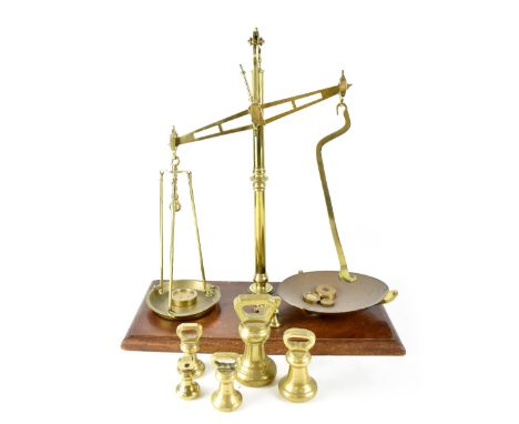 An early 20th century set of Avery scales and weights, brass column supporting two brass weighing pans, with four weights, on