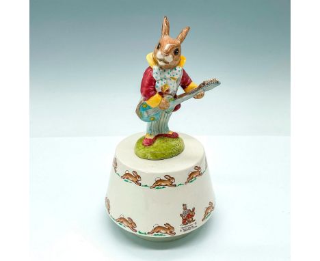 Vintage music box featuring a bunny playing guitar atop a beige-toned porcelain base with an enchanting design of hopping rab