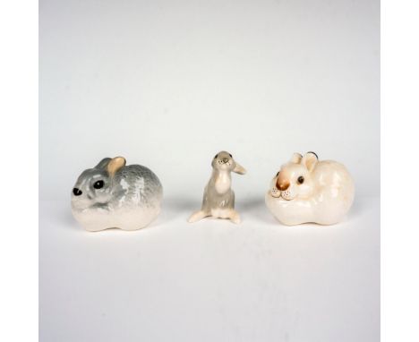A set of 3 ceramic figures consisting of a white and dark gray rabbit sitting on all fours along with one skinny light gray r