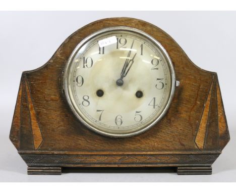 An oak cased Art Deco mantel clock with silvered dial chiming on a coiled gong.