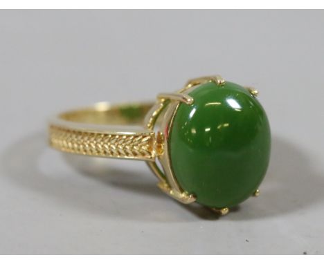 An 18ct gold ring set with a cabochon jade tablet and with wreath moulded shoulders, size N, 4.9 grams.