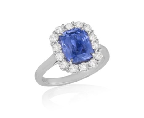 A SAPPHIRE AND DIAMOND CLUSTER RINGSet with a cushion-shaped sapphire weighing 3.62cts, within a four-claw setting, to a bril