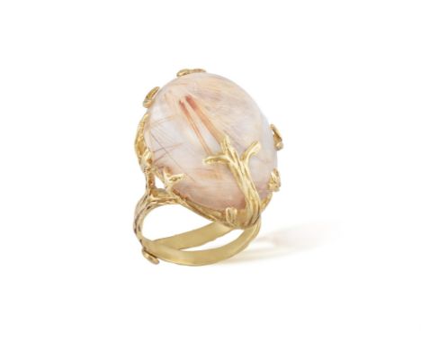 A QUARTZ COCKTAIL RINGSet with an oval-shaped rutile quartz cabochon, within a scrolled textured gold naturalistic mount, mou
