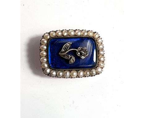A 19th century yellow metal rectangular brooch with central diamond chip flower on blue enamel ground, with seed pearl border