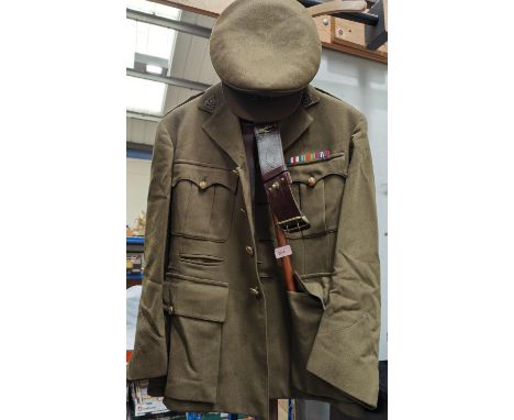 A WWII period Royal Army Ordinance Corps uniform with buttons and badges to collar and cap, leather belts and wooden stick 