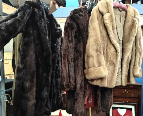 A light fur half length coat and two longer dark fur coats 