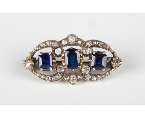 A diamond, sapphire and blue paste set brooch, claw set with an oval cut sapphire between two square step cut blue pastes, ot