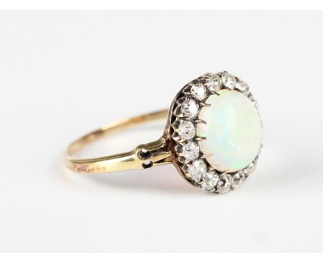 A gold, opal and diamond cluster ring, claw set with the oval opal within a surround of cushion cut diamonds between split sh