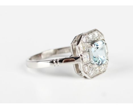 A platinum, aquamarine and diamond square cluster ring, claw set with the cut cornered square step cut aquamarine within a su
