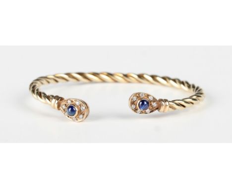 A 9ct gold, cabochon sapphire and colourless gem set bangle in a ropetwist design with pear shaped terminals, each mounted wi