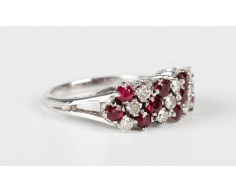 A white gold, ruby and diamond ring in a slanting design, claw set with four rows of circular cut rubies alternating with thr