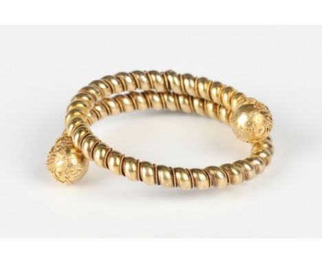 A gold circular sprung bangle, each terminal of spherical form with applied wirework decoration, otherwise in a ropetwist des