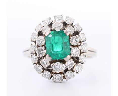 14 kt. Witgouden ring, centraal bezet met een emerald cut geslepen smaragd ca. 7 x 6 mm) in een dubbele entourge van briljant