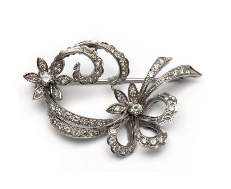 18 kt. Witgouden strikbroche, jaren ' 60, met een decor van krullen en bloemen, bezet met briljant geslepen diamant, totaal c