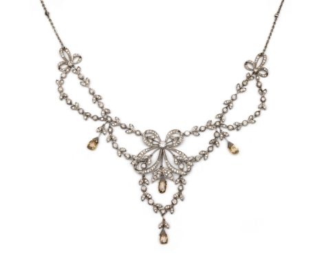 18 kt. Witgouden festoen collier in Belle Epoque stijl. De voorzijde rijkelijk gedecoreerd met strikken en guirlandes en het 