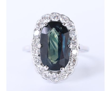 14 kt. Witgouden met platina ring, centraal bezet met een donkerblauwe ovale saffier ( (13,7 x 8,4 mm) in een entourage van b