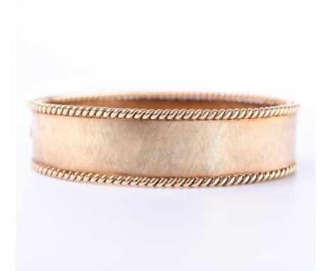 14 kt. Gouden stijve armband, het oppervlak gearceerd en afgezet met een torsrand bruto 33,2 gr., binnenmt. 66 x 49 mm, b. 18