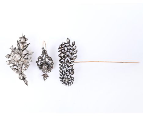 14 kt. Goud met zilveren broche, in de vorm van een tak met bloemen, bezet met roosgeslepen diamant. Hierbij een enkele goud 