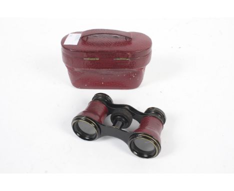  A vintage pair of red leather covered opera glasses in a case, stamped Chevalier Paris.