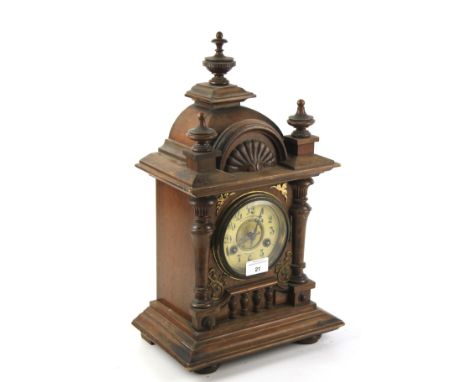 An early 20th century mantel clock. The enamel dial with Arabic numerals and marked Pleasance &amp; Harper, in a carved oak c