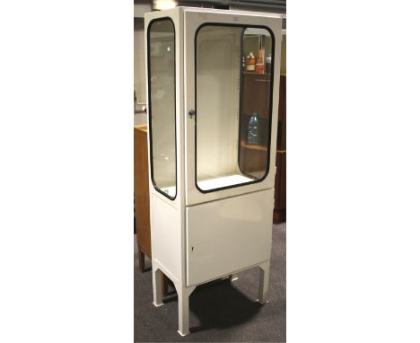 A vintage 1970s white painted glazed metal single medical cabinet. With glazed lockable door above a cupboard, on square supp