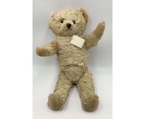 A 1930's Knickerbocker blonde plush covered teddy bear with cast metallic nose, amber eyes, jointed limbs, canvas covered pad