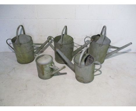 A collection of five vintage galvanised watering cans