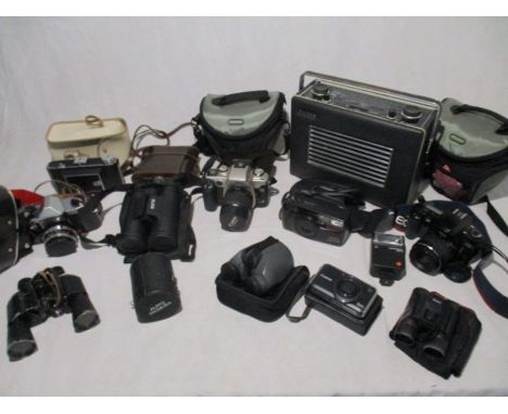 A collection of camera's, binoculars and accessories including Canon, Praktica etc, along with a vintage Hacker radio. 