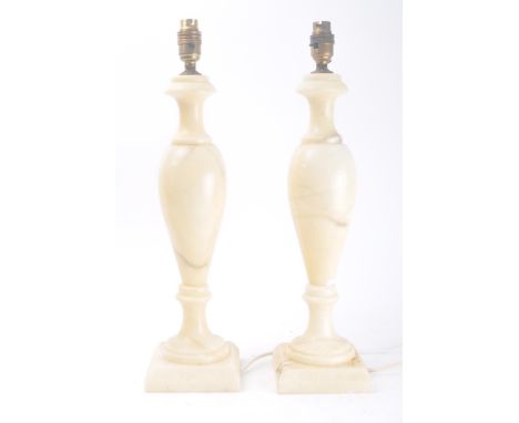 A pair of mid 20th Century alabaster table / bedside lamps. Each lamp cream in colourway and of a vase shaped form. Mounted a