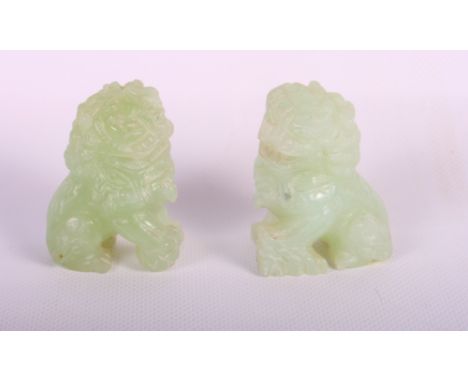 A pair of oriental carved jade models of temple dogs, 2" high