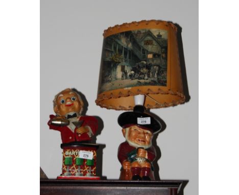 A Rosco battery operated automaton of a bartender and a Toby jug table lamp base with parchment shade decorated coaching scen