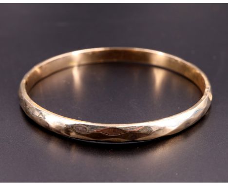 A faceted 9 ct yellow metal D-section circular bangle, 75 mm internally, 10.5 g