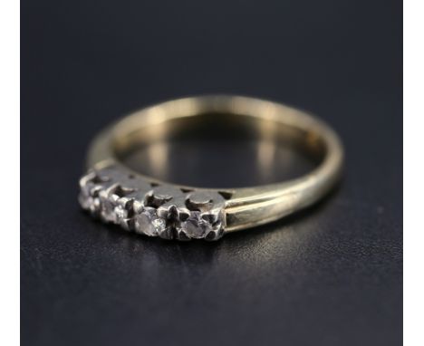 A vintage four stone diamond and yellow metal ring, having four 2 mm brilliants line set in a white metal gallery between ree