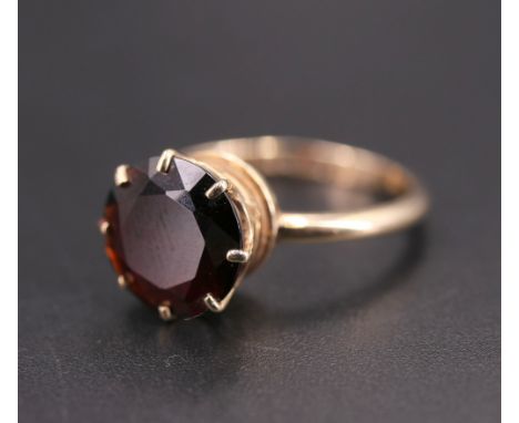 A 1970s garnet dress ring, the circular facet-cut stone (10 mm) crown-set on a 9 ct gold shank, N/O, HE, London, 1974