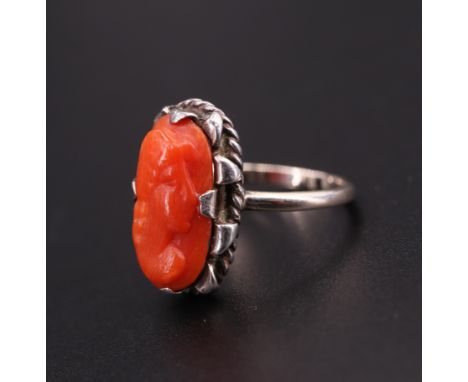 A relief-carved coral finger ring, depicting a female profile bust, set on a 9 ct yellow metal shank, 17 mm x 10 mm, N, 3.5 g