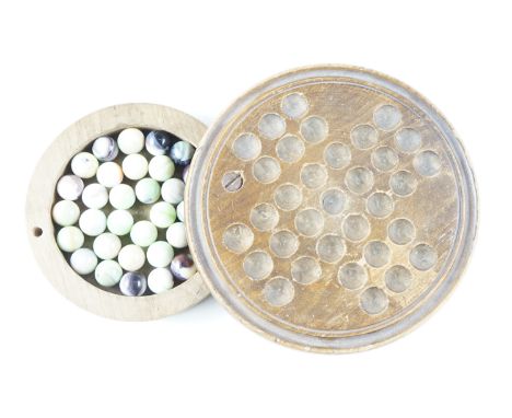 A vintage turned wood solitaire board, the compartment containing a quantity of glass marbles, board 15 cm diameter