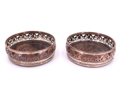 A pair of early 19th Century Sheffield plate decanter coasters, having pierced ovoid sides of scrolling acanthus and turned m