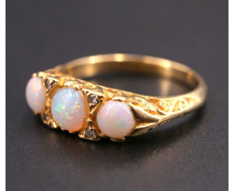 An early 20th Century opal and diamond ring, having three graduated opal cabochons (4 mm and 5 mm), each separated by two sma