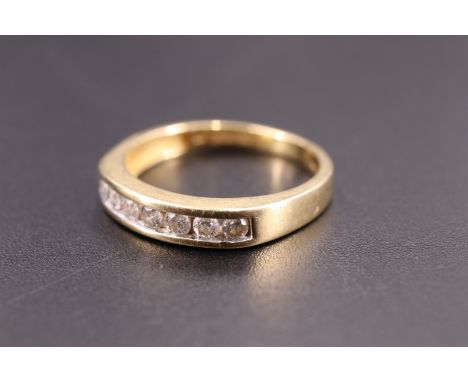 A modern diamond and 18 ct ring, having seven brilliants (0.23 carats aggregate) channel set between gently tapering shoulder