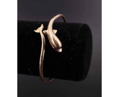 A late 20th Century 14 ct yellow metal naturalistic bangle, having a coiled band merging to terminate in a dolphin's head and