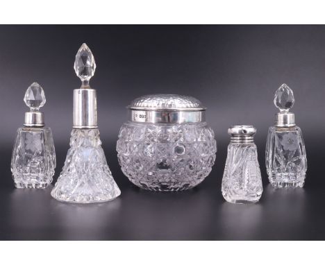 Four early 20th Century silver mounted scent bottles together with a silver mounted lidded pot of compressed grenade form, fi