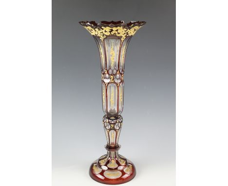 An early 20th Century Bohemian ruby glass vase, of tall slender baluster form, ruby flashed and faceted and having scrolling 