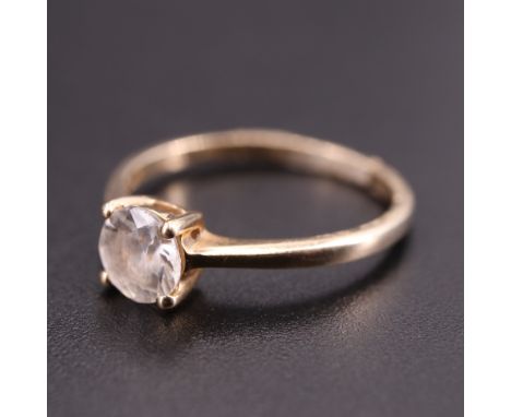 A modern white sapphire 9 ct gold solitaire ring, having a 5.5 mm brilliant claw set on a gallery between tapering shoulders,