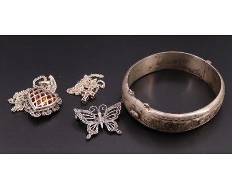 An early 1960s engraved silver hinged bangle together with a marcassite butterfly brooch, a heart-shaped marcassite and amber