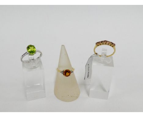 Three 9 carat gold gemset dress rings to include a white gold peridot ring,  UK ring sizes N & O (3) 