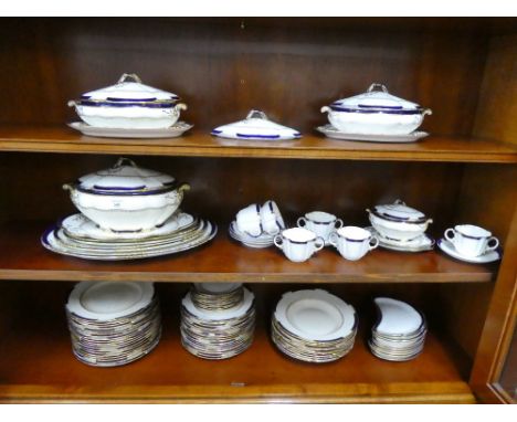 George Jones and Sons white glazed dinner service with oval blue borders and gilt highlights comprising tureens, serving dish