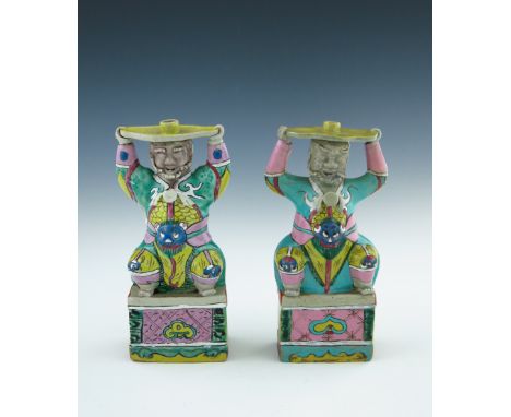 A pair of Chinese coloured enamel porcelain candle holders, in the form of smiling bearded men in robes, their hats forming t