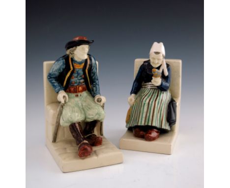 Bouvier, a pair of Quimper figural bookends, modelled as an old Dutch woman spinning and a man with crutches, signed, 23.5cm 