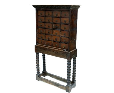 A 17th century and later wooden apothecary chest on stand, the upper section comprising acanthus carved cornice over a bank o